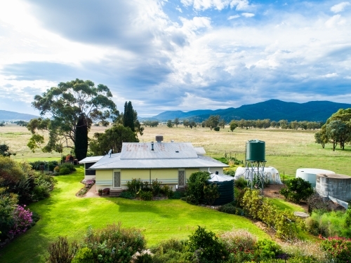 Green front lawn and garden of farm homestead house seen from aerial view on aussie property - Australian Stock Image