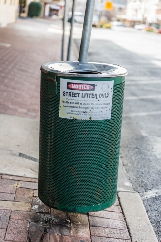 Green rubbish bin on street with litter notice - Australian Stock Image