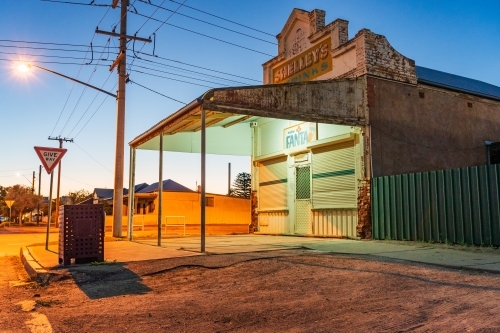 Ground level view of an old fashioned corner store at twilight with streets and power lines