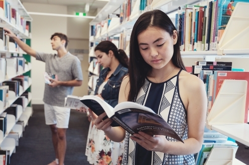 Group of international students reading in university library - Australian Stock Image