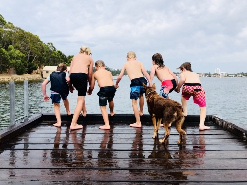 Group of kids jumping off a wharf into the water