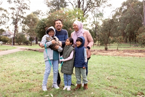 Group of people in a big lawn with one boy holding a cat on a leash - Australian Stock Image