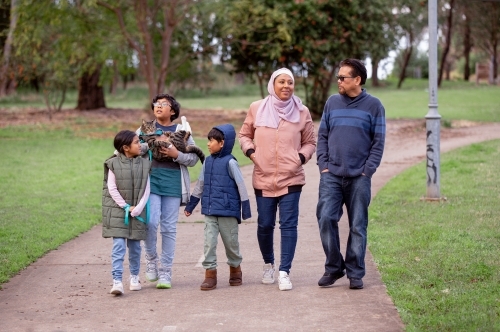 Group of people with one woman wearing pink hijab and a middle aged man three children and a cat - Australian Stock Image