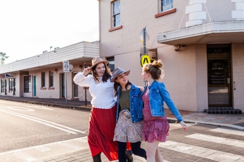Group of three best friends walking down main street of country town in rural Australia - Australian Stock Image