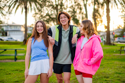 Group of young people socialising and having fun in a park on a warm evening - Australian Stock Image