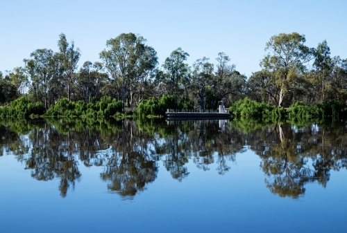 gum trees and barge reflected on still river - Australian Stock Image