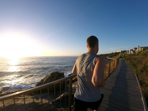 Guy jogging near ocean at sunrise