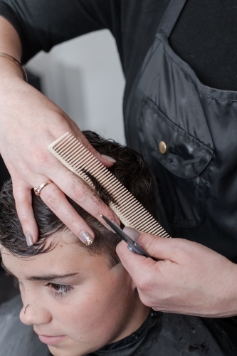 Hairdresser cutting teenage boys hair