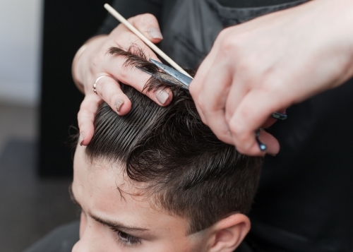 Hairdresser cutting teenage boys hair - Australian Stock Image