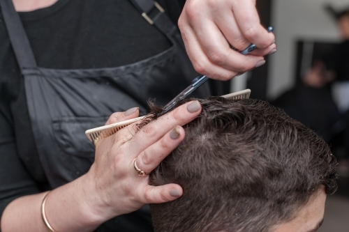 Hairdresser cutting teenage boys hair - Australian Stock Image