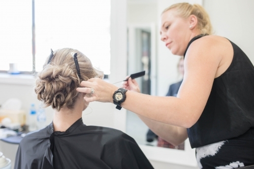 Hairdresser styling hair with comb - Australian Stock Image