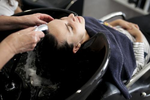 Hairdresser washing a woman's hair at a salon - Australian Stock Image