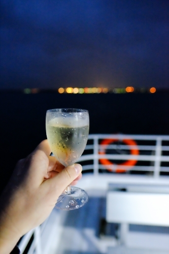 Hand holding a glass of white wine on a boat at night