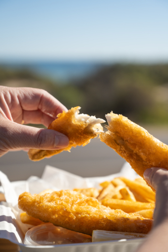 hands breaking open fish and chips - Australian Stock Image