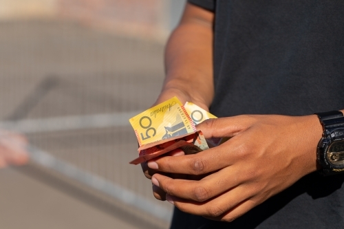 hands holding a variety of polymer notes as cash