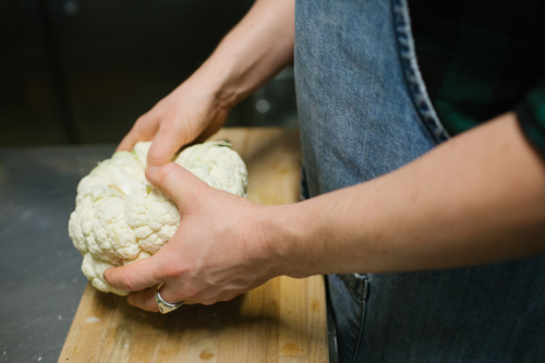 Hands in kitchen breaking cauliflower - Australian Stock Image