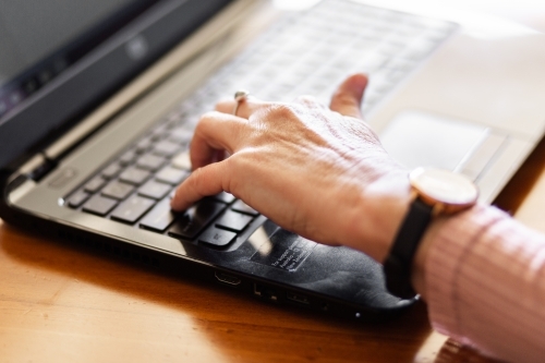 Hands of older woman typing on laptop - Australian Stock Image