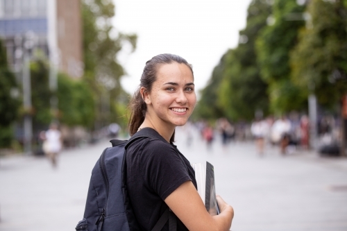 Happy aboriginal female university student holding textbooks  - Australian Stock Image