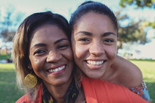 Happy African mother and multicultural teen daughter close up