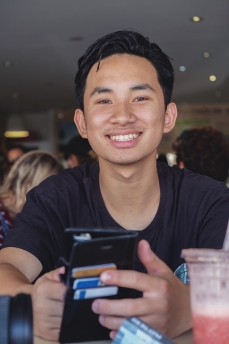 Happy Asain teen boy in juice bar - Australian Stock Image