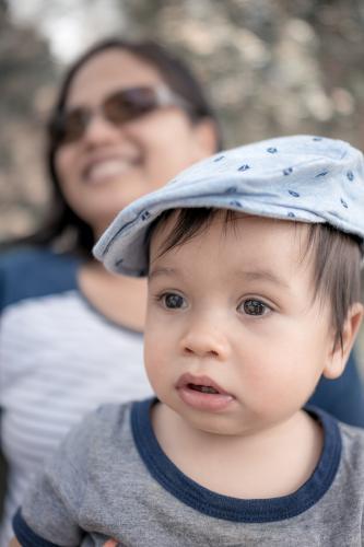 Happy Asian mum talking to her friends with her mixed race baby boy outside - Australian Stock Image