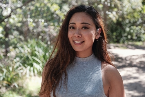 Happy Asian young adult woman in the park - Australian Stock Image