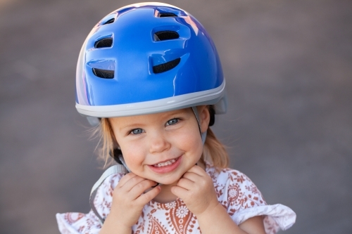 Happy Aussie toddler wearing bike helmet for safety while riding - Australian Stock Image