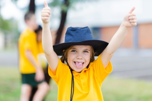 Happy Australian school girl with thumbs up and tongue out - Australian Stock Image