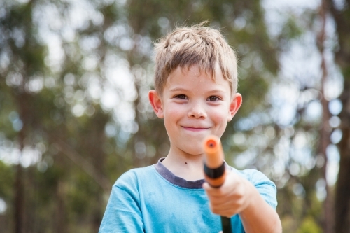 Happy boy holding out a garden hose - Australian Stock Image