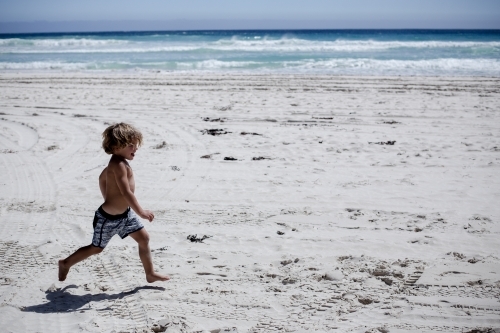 Happy boy running at beach - Australian Stock Image