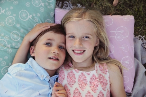 Happy brother and big sister lying in the park - Australian Stock Image