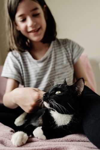 Happy child patting her pet cat in her bedroom.