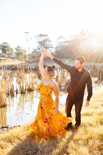 Happy couple spin together beside dam - Australian Stock Image