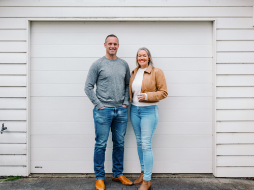 Happy couple stands in the driveway of their new home - Australian Stock Image