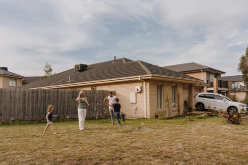 Happy family blowing and playing with bubbles in their yard. - Australian Stock Image