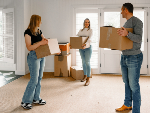 Happy family carrying boxes into their new home - Australian Stock Image