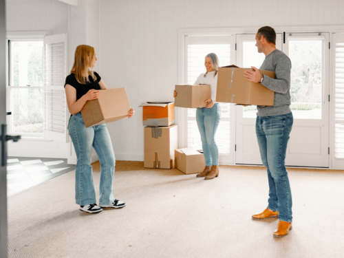 Happy family carrying boxes into their new home - Australian Stock Image
