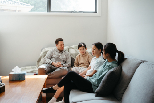 Happy family gathered and seated in the entertainment room. - Australian Stock Image
