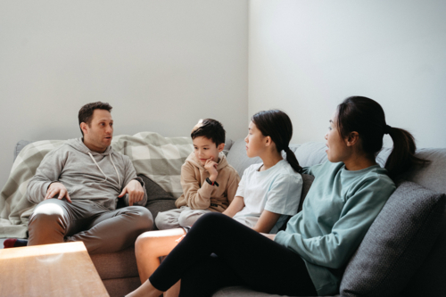 Happy family gathered and seated in the entertainment room. - Australian Stock Image