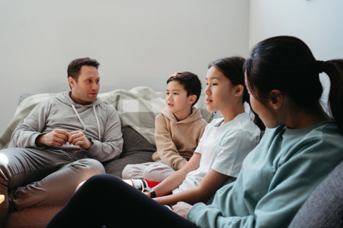 Happy family gathered and seated in the entertainment room. - Australian Stock Image