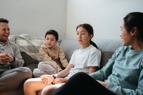 Happy family gathered and seated in the entertainment room. - Australian Stock Image