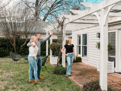 Happy family gathered in the patio of their new home with adult man pointing towards patio rafter - Australian Stock Image