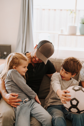 Happy family lounging in the couch in the living room. - Australian Stock Image