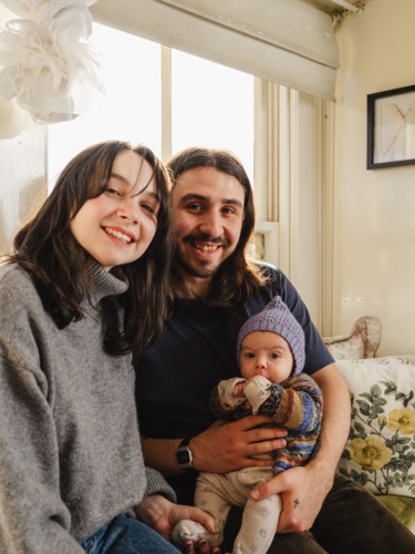 Happy family sitting together near windows inside brightly lit home - Australian Stock Image