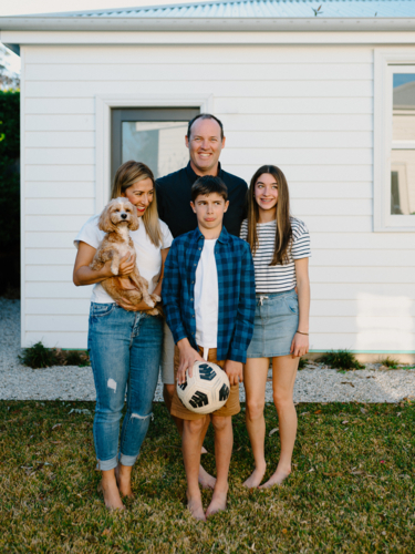 Happy family standing barefoot in their yard. - Australian Stock Image