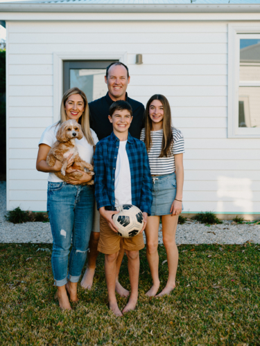 Happy family standing barefoot in their yard. - Australian Stock Image