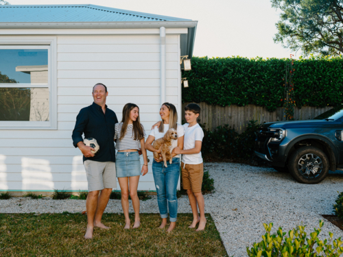 Happy family standing barefoot in their yard. - Australian Stock Image