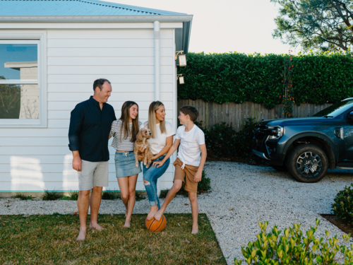 Happy family standing barefoot in their yard. - Australian Stock Image
