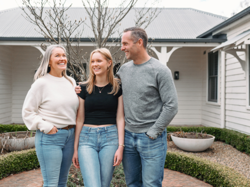 Happy family standing in the front yard of their new home - Australian Stock Image