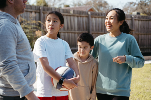 Happy family standing outside in their yard. - Australian Stock Image